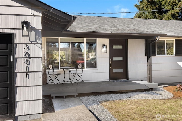doorway to property with a shingled roof