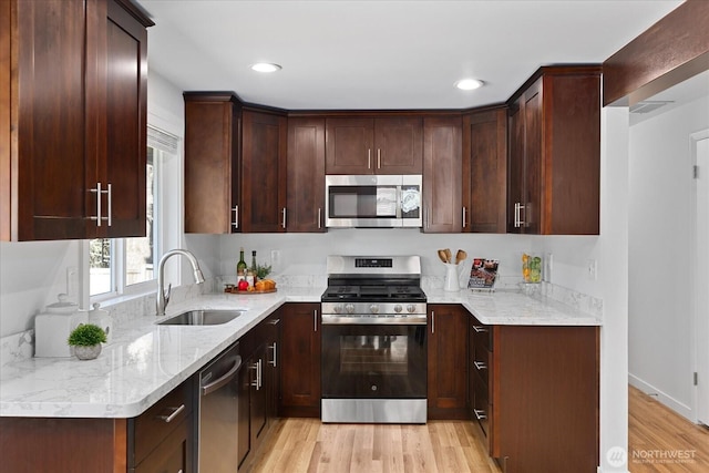 kitchen with light wood-style flooring, a sink, recessed lighting, dark brown cabinetry, and appliances with stainless steel finishes