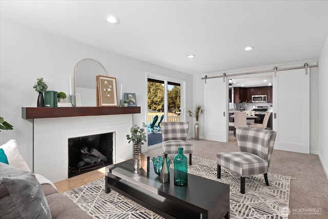 living area with baseboards, a barn door, light carpet, recessed lighting, and a fireplace