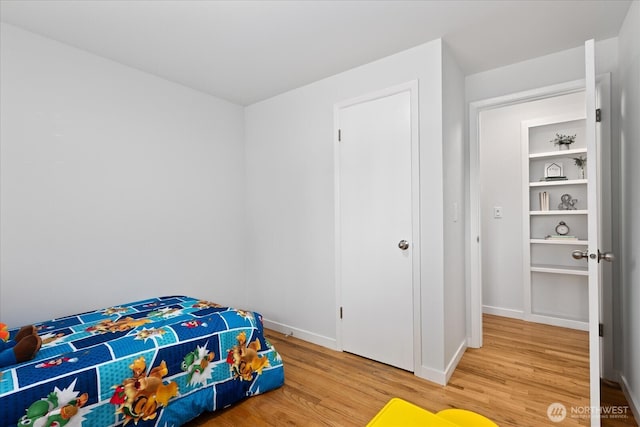bedroom with light wood-type flooring and baseboards