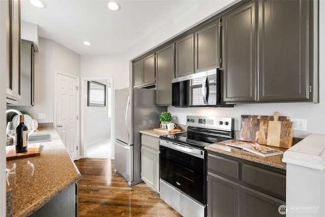 kitchen featuring dark wood-type flooring, light stone countertops, recessed lighting, appliances with stainless steel finishes, and a sink