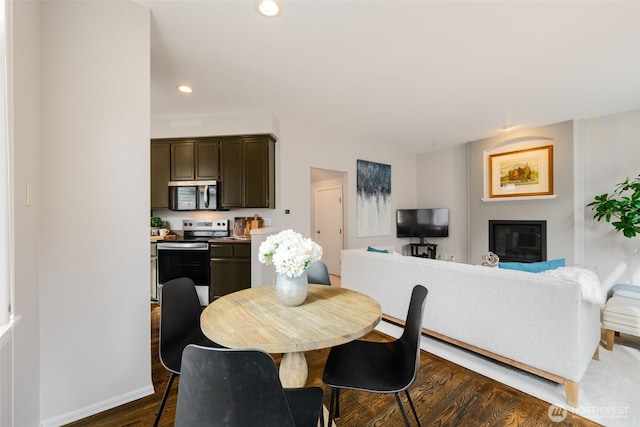 dining area featuring dark wood finished floors, a glass covered fireplace, recessed lighting, and baseboards