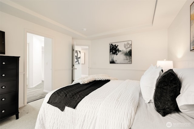 bedroom featuring a tray ceiling and light carpet