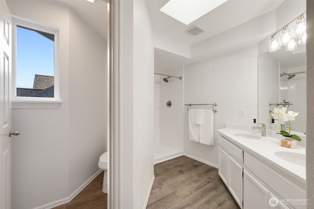 bathroom with wood finished floors, visible vents, a skylight, a sink, and a shower