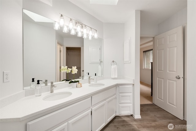 bathroom featuring a sink, wood finished floors, and a skylight