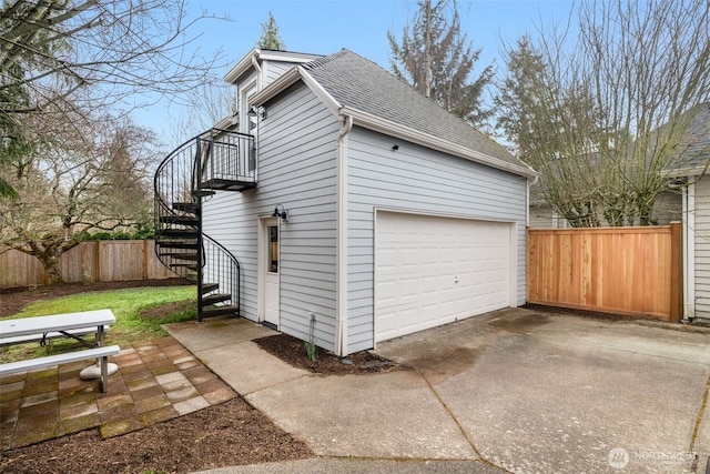 garage with concrete driveway and fence