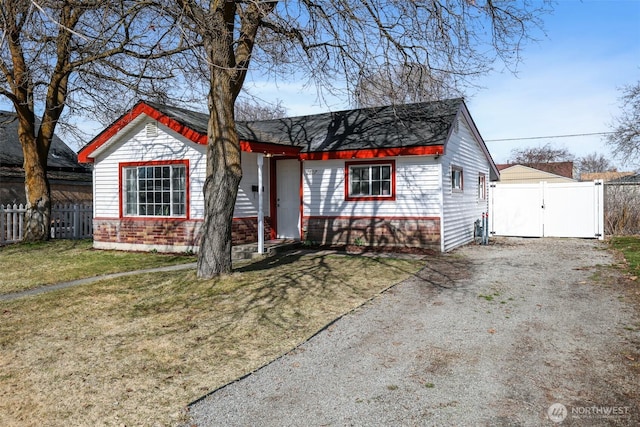 view of front of house featuring a front yard, a gate, fence, driveway, and brick siding