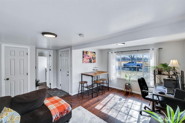 living area featuring baseboards, a textured ceiling, and wood finished floors