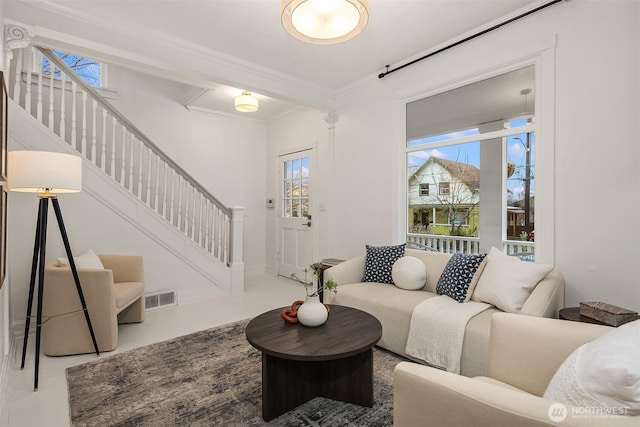 living room featuring stairs, crown molding, plenty of natural light, and visible vents