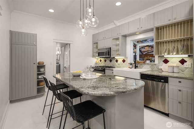 kitchen with decorative backsplash, appliances with stainless steel finishes, crown molding, and a kitchen breakfast bar