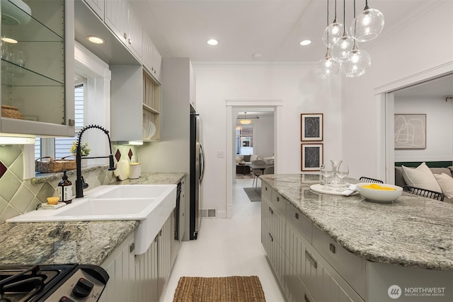 kitchen with a sink, backsplash, a kitchen island, appliances with stainless steel finishes, and light stone countertops