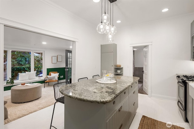 kitchen with black range with gas stovetop, gray cabinetry, a kitchen island, light stone countertops, and ornamental molding