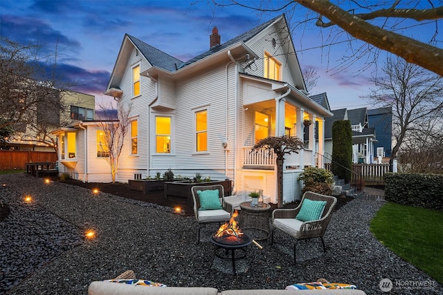 back of property at dusk featuring a fire pit and a chimney