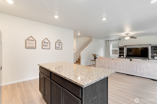 kitchen with light stone countertops, baseboards, recessed lighting, light wood-style floors, and a center island