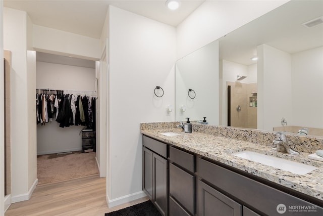 full bath with a sink, visible vents, a walk in closet, and a stall shower