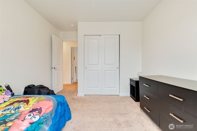 bedroom featuring a closet, light carpet, and baseboards