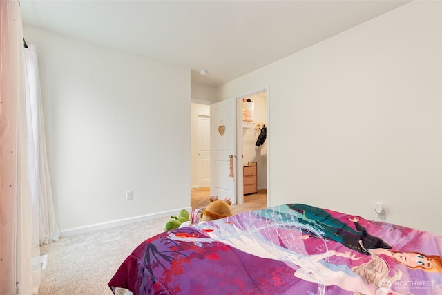 bedroom featuring a spacious closet, light colored carpet, and baseboards