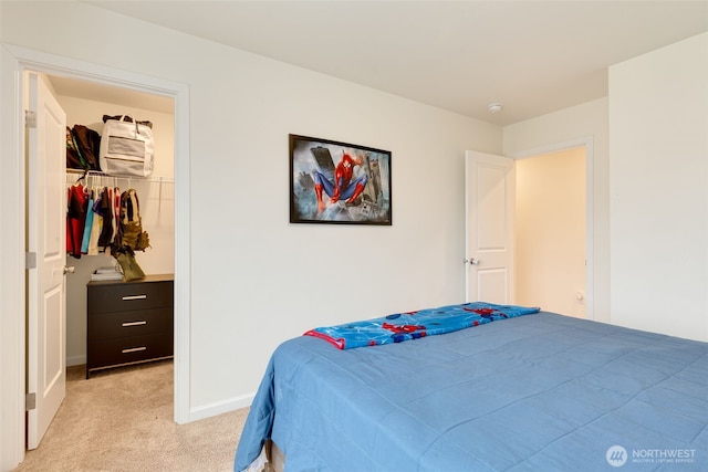 bedroom with a closet, baseboards, light colored carpet, and a spacious closet