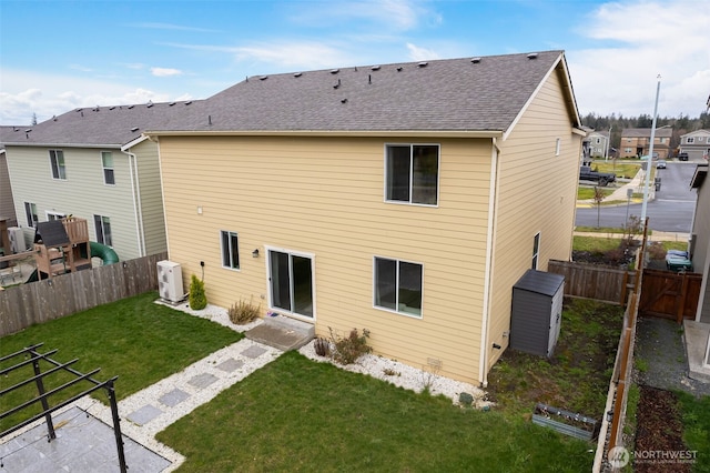 rear view of house featuring a fenced backyard, ac unit, a yard, and roof with shingles