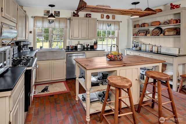 kitchen featuring open shelves, wooden counters, appliances with stainless steel finishes, and brick floor