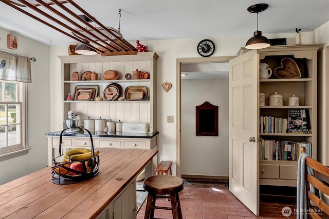 kitchen featuring wooden counters, pendant lighting, brick floor, and open shelves