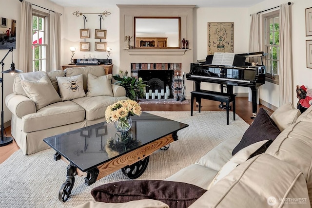 living room with a brick fireplace and wood finished floors