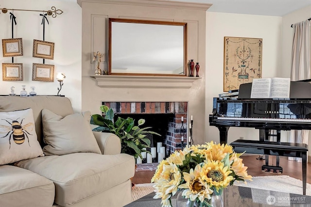 living room with a brick fireplace and wood finished floors