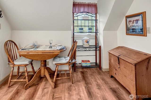 dining room with baseboards, wood finished floors, and vaulted ceiling