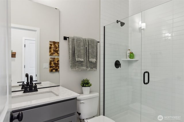 bathroom with toilet, a stall shower, and vanity