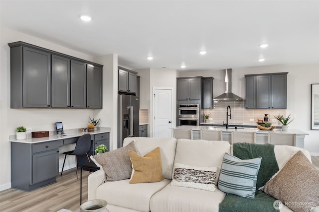 living area with recessed lighting, built in desk, light wood-style flooring, and baseboards