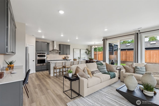 living area featuring a notable chandelier, light wood-style floors, and recessed lighting