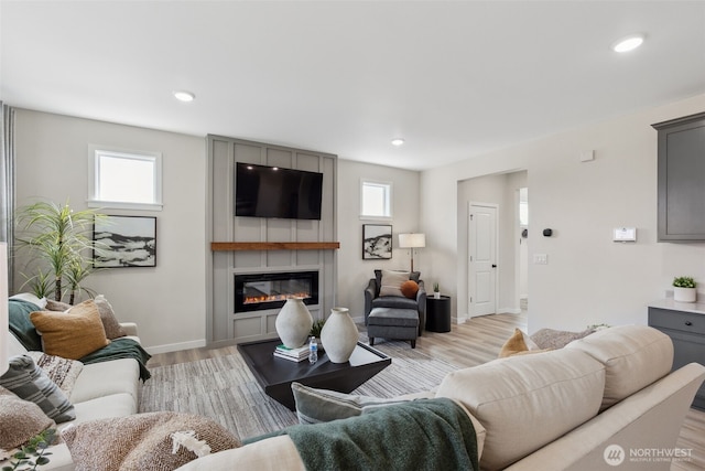 living area featuring light wood finished floors, recessed lighting, a fireplace, and baseboards