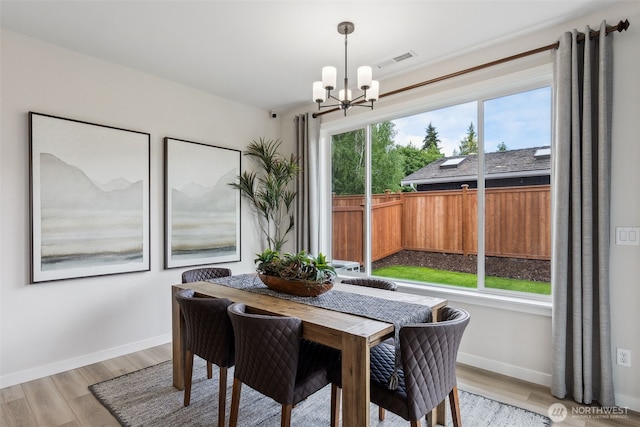 dining space with visible vents, baseboards, an inviting chandelier, and light wood-style flooring