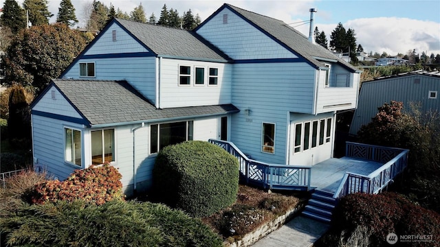 rear view of property with a deck and a shingled roof