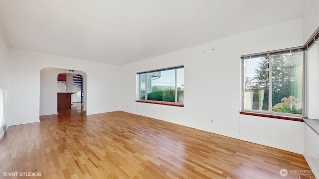 spare room with arched walkways and light wood-style floors