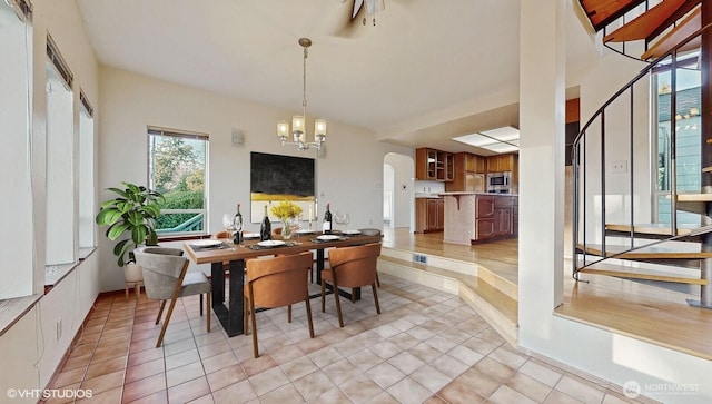 dining room with light tile patterned floors, visible vents, arched walkways, and a chandelier