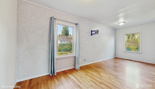 empty room with visible vents, crown molding, baseboards, and wood finished floors