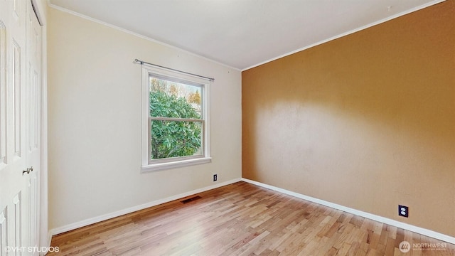 empty room with visible vents, baseboards, wood finished floors, and ornamental molding