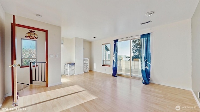 unfurnished room featuring visible vents, baseboards, and wood finished floors