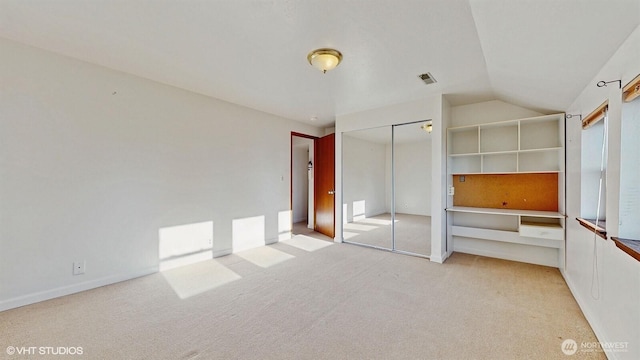 unfurnished bedroom featuring vaulted ceiling, carpet, visible vents, and a closet