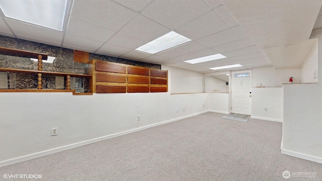 finished basement featuring a paneled ceiling, baseboards, and carpet floors