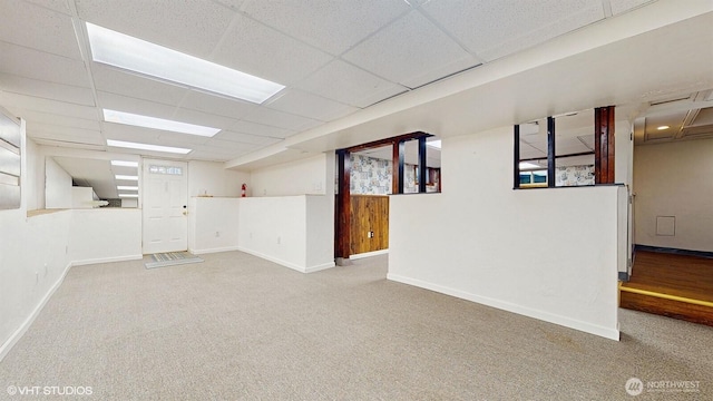 finished basement featuring carpet flooring, baseboards, and a drop ceiling