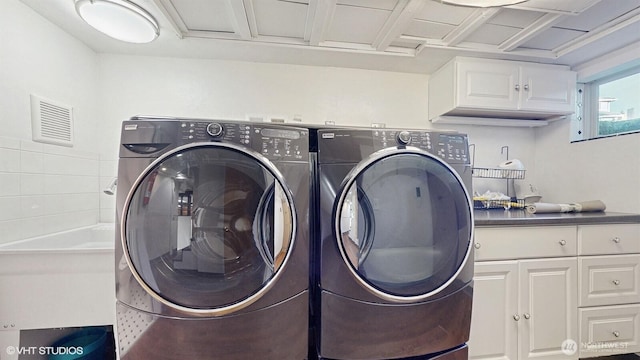 washroom featuring washer and clothes dryer, visible vents, and cabinet space