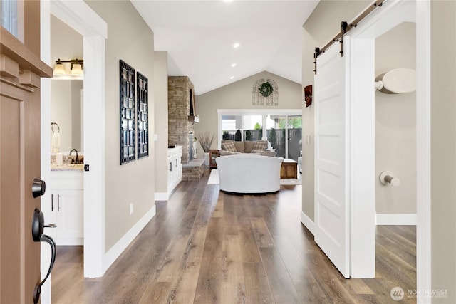 foyer with baseboards, a barn door, vaulted ceiling, recessed lighting, and wood finished floors