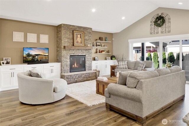 living room with recessed lighting, light wood-style flooring, a fireplace, and high vaulted ceiling