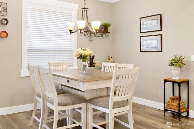 dining room with light wood-style floors, baseboards, and a chandelier