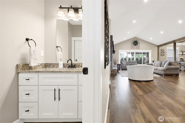 bathroom featuring vanity, wood finished floors, lofted ceiling, a freestanding tub, and recessed lighting