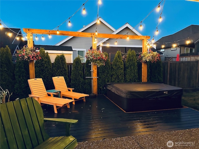 view of patio with a wooden deck, a covered hot tub, and fence