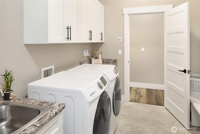 washroom with a sink, wood finished floors, cabinet space, baseboards, and washing machine and clothes dryer