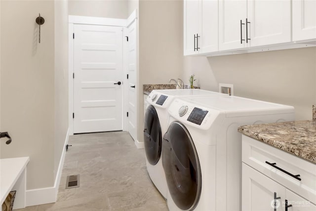 clothes washing area featuring washer and dryer, cabinet space, visible vents, and baseboards